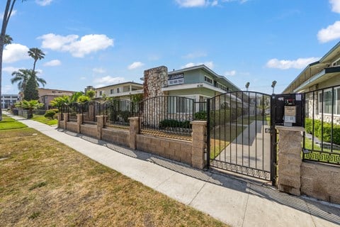 a gated entrance to a building with palm trees in the background